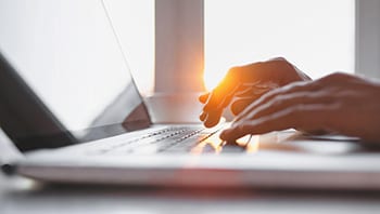 Image of person typing on a laptop