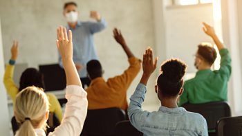 Photo of students raising hands in classroom